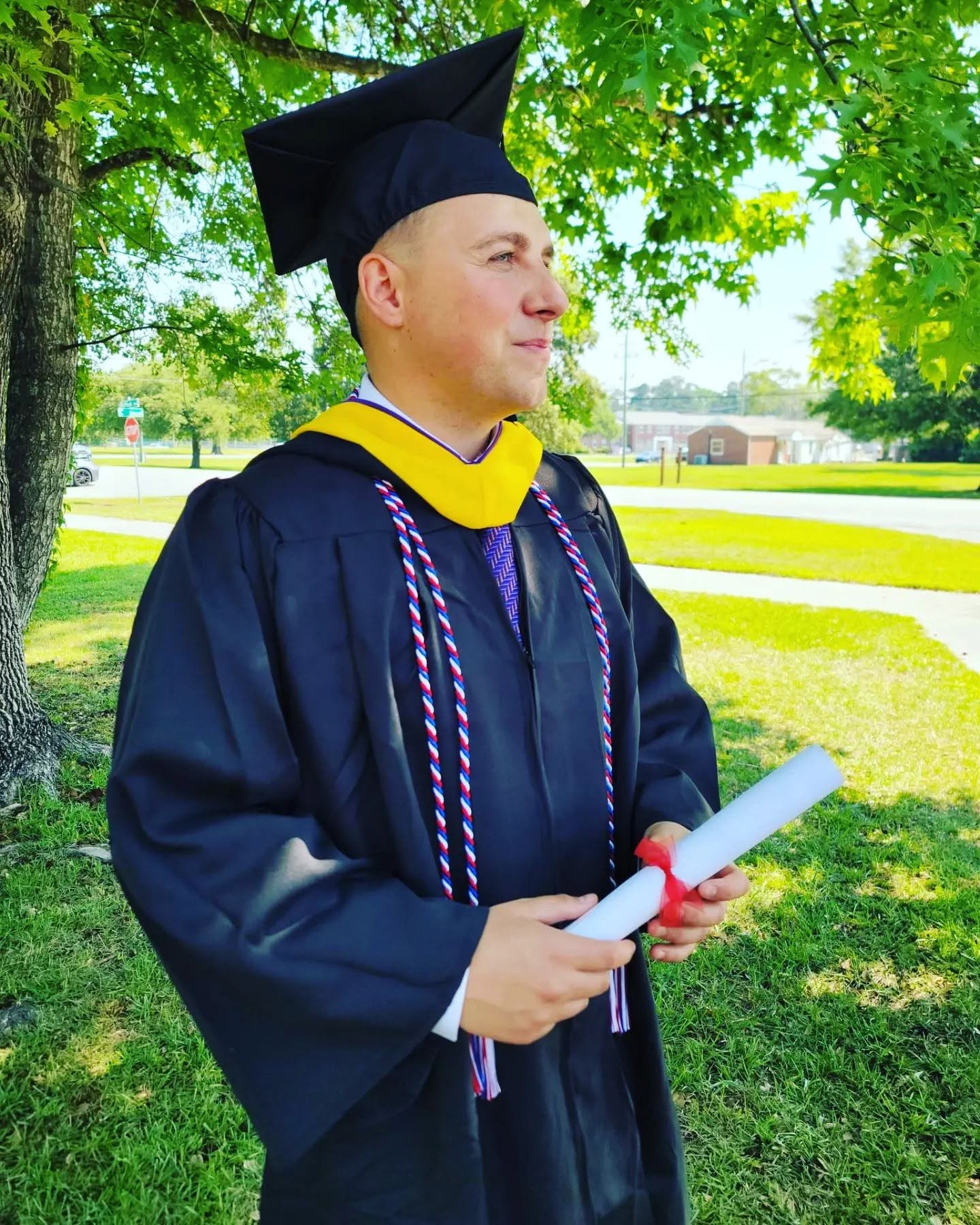 Devyn Harrington in graduation regalia holding his diploma